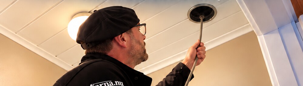 Sotare rengör ett ventilationsdon i taket
